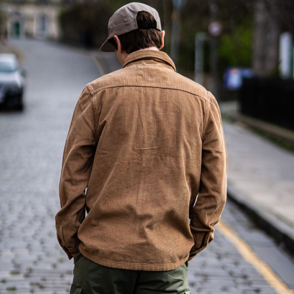 A person wearing a Paradaiza tan corduroy overshirt with a collar, buttons, and a patch chest pocket.