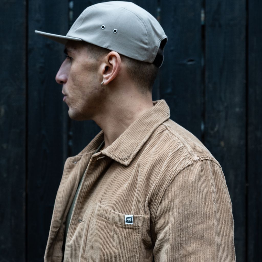 A person wearing a Paradaiza tan corduroy overshirt with a collar, buttons, and a patch chest pocket.