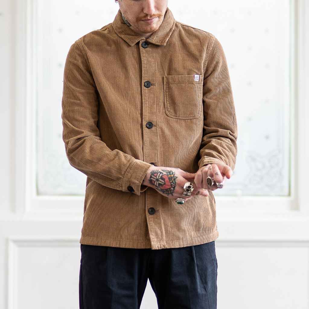 A person wearing a Paradaiza tan corduroy overshirt with a collar, buttons, and a patch chest pocket.