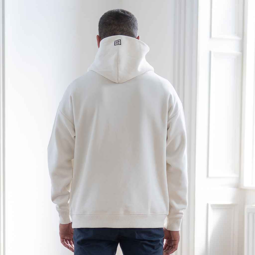 A male model wearing an oversized Paradaiza hooded sweatshirt in off white color