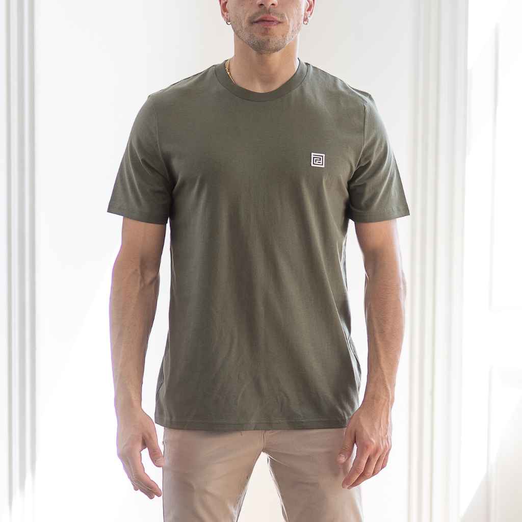 A male model wearing a short-sleeved Paradaiza khaki green crewneck t-shirt with a small branded logo on the chest.