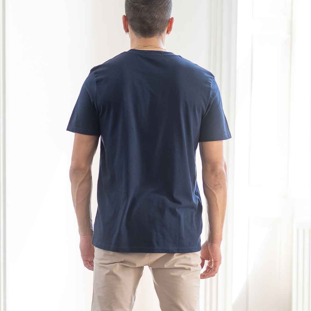 A man wearing a navy blue classic paradaiza crewneck T-shirt with a small white logo on the chest.