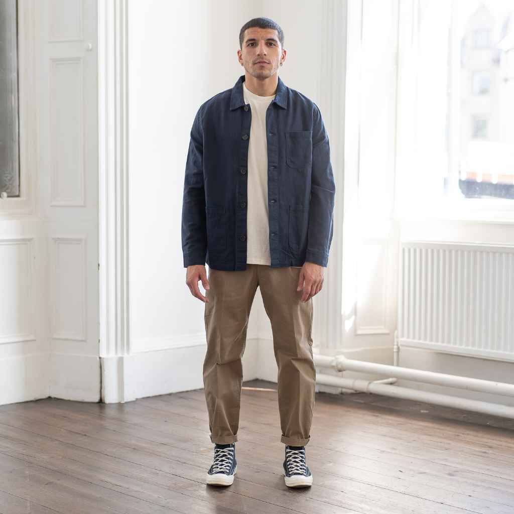 A man wearing a Paradaiza navy-colored worker jacket with long sleeves, featuring a collar, button-up front, and two patch pockets on the hem.