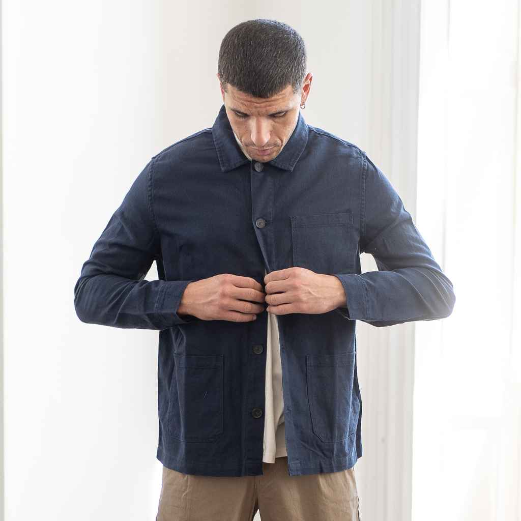 A man wearing a Paradaiza navy-colored worker jacket with long sleeves, featuring a collar, button-up front, and two patch pockets on the hem.