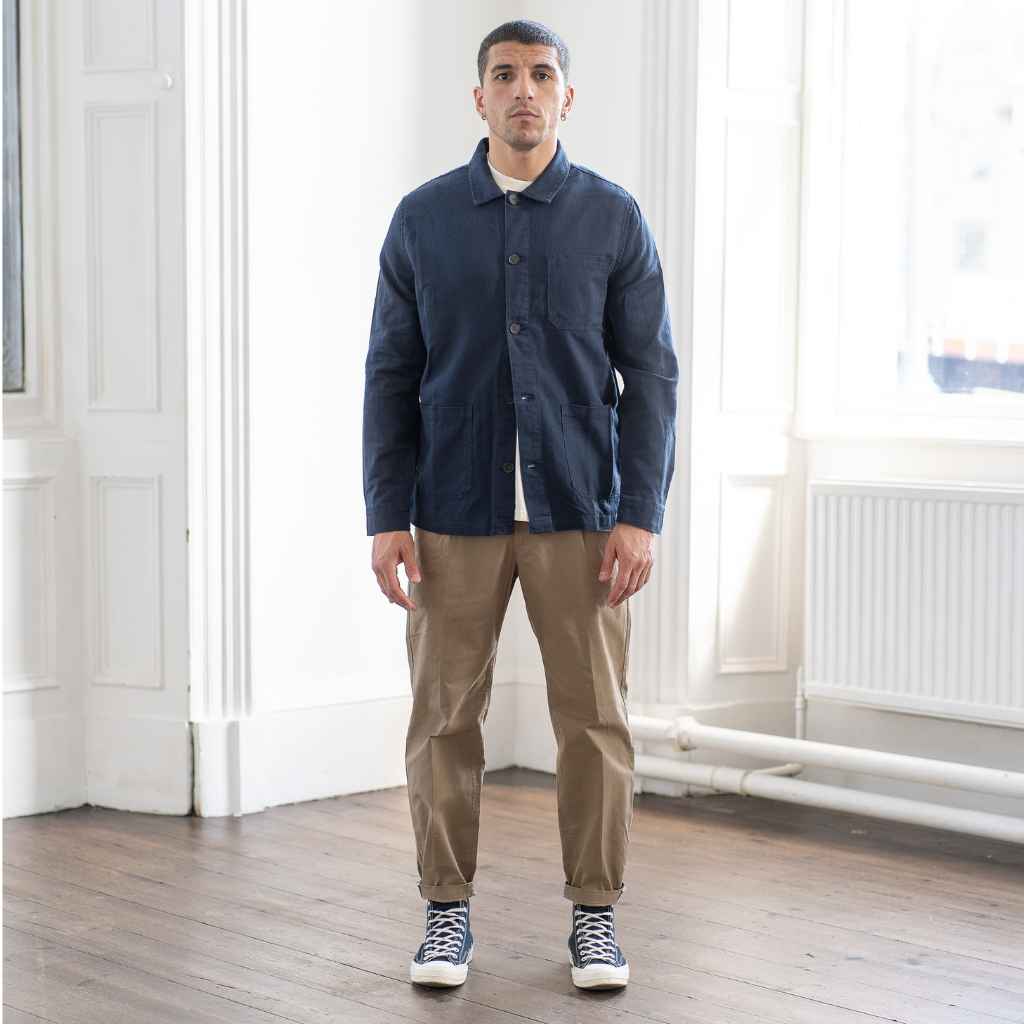 A man wearing a Paradaiza navy-colored worker jacket with long sleeves, featuring a collar, button-up front, and two patch pockets on the hem.