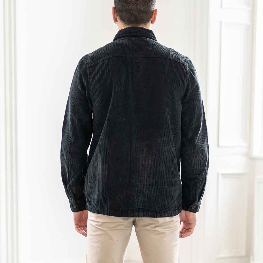 A male model wearing a para daiza long-sleeved black overshirt with a collar, patch chest pocket, and buttons down the front.