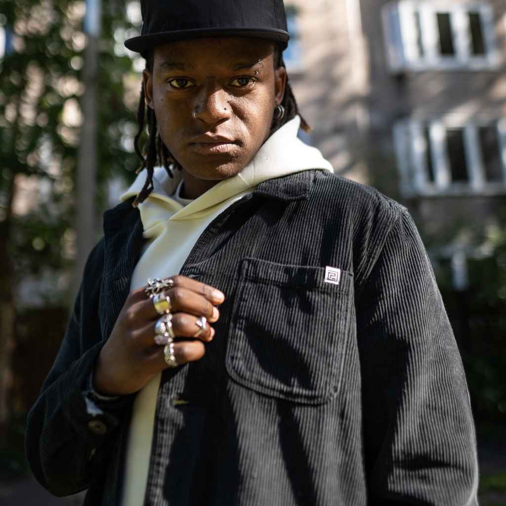 A male model wearing a para daiza long-sleeved black overshirt with a collar, patch chest pocket, and buttons down the front.