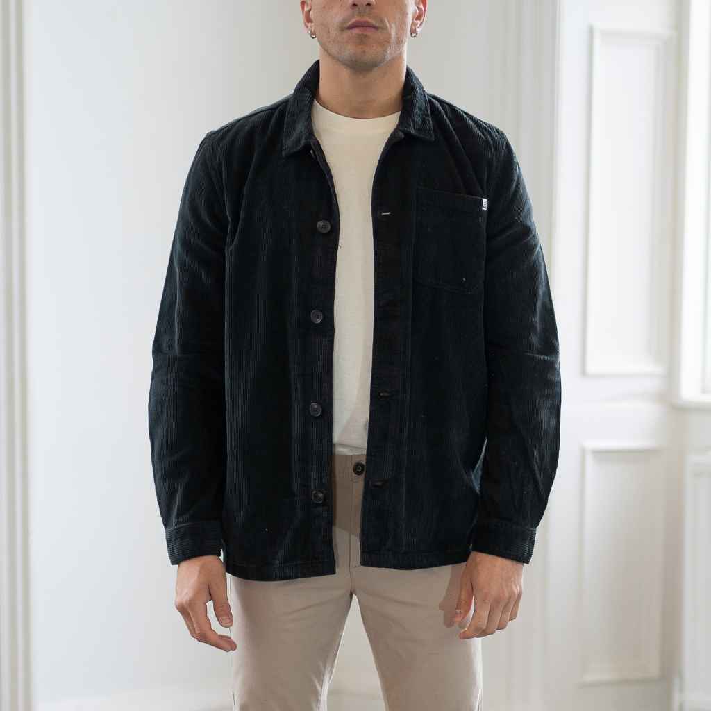 A male model wearing a para daiza long-sleeved black overshirt with a collar, patch chest pocket, and buttons down the front.
