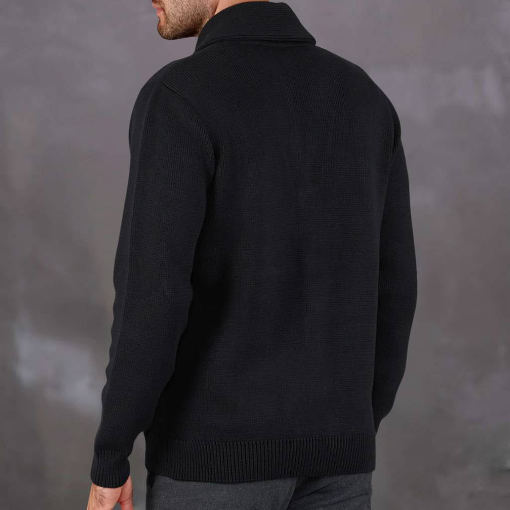 Man wearing a navy paradaiza cardigan over a red shirt against a gray background