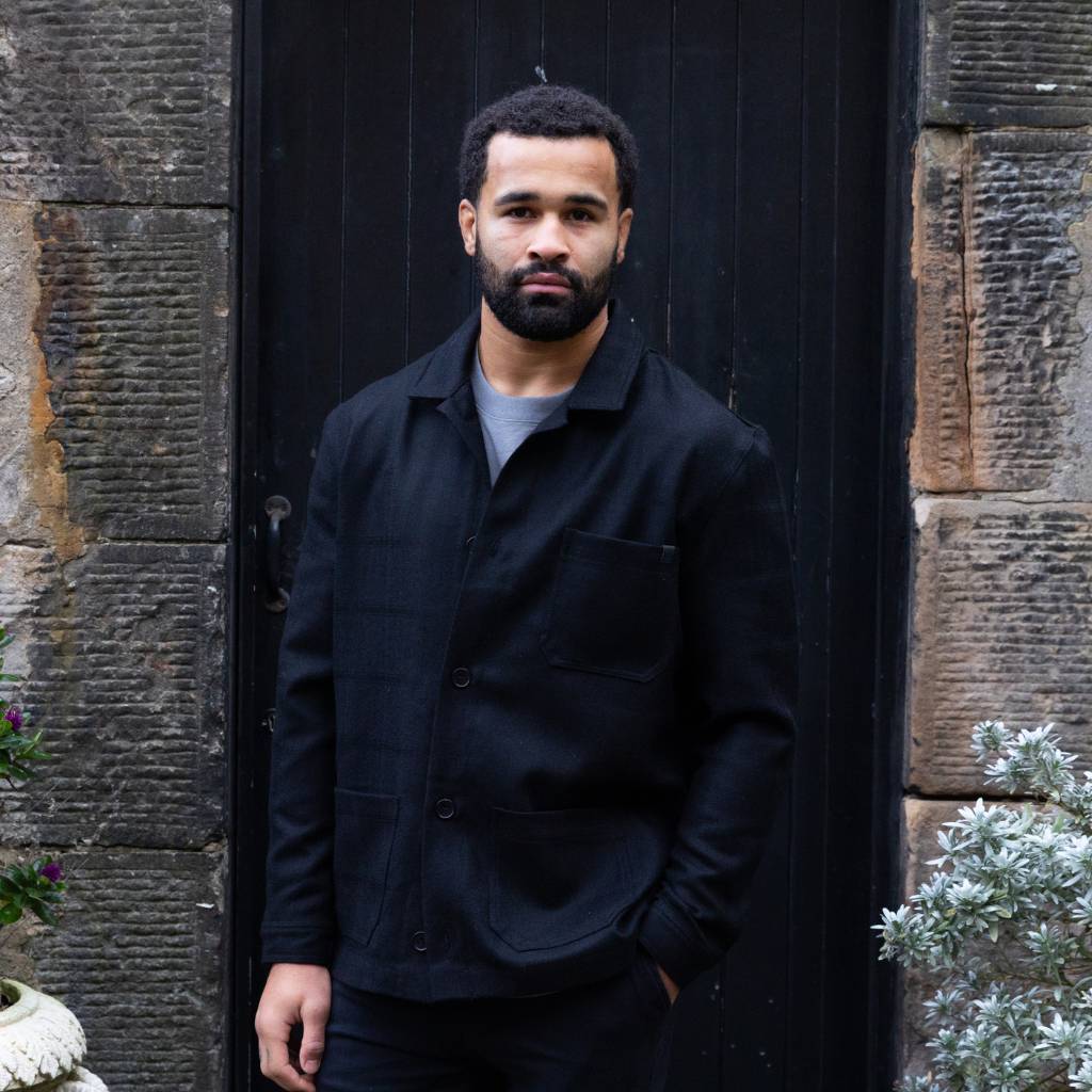 Man wearing a  paradaiza wool worker black jacket standing in front of a stone wall in circus lane stockbridge 