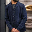 Man wearing a navy paradaiza cardigan over a red shirt against a gray background