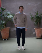 Man wearing a paradaiza brown sweater over a light blue shirt against a gray background