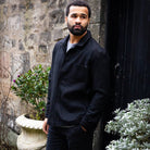 Man wearing a  paradaiza wool worker black jacket standing in front of a stone wall in circus lane stockbridge 