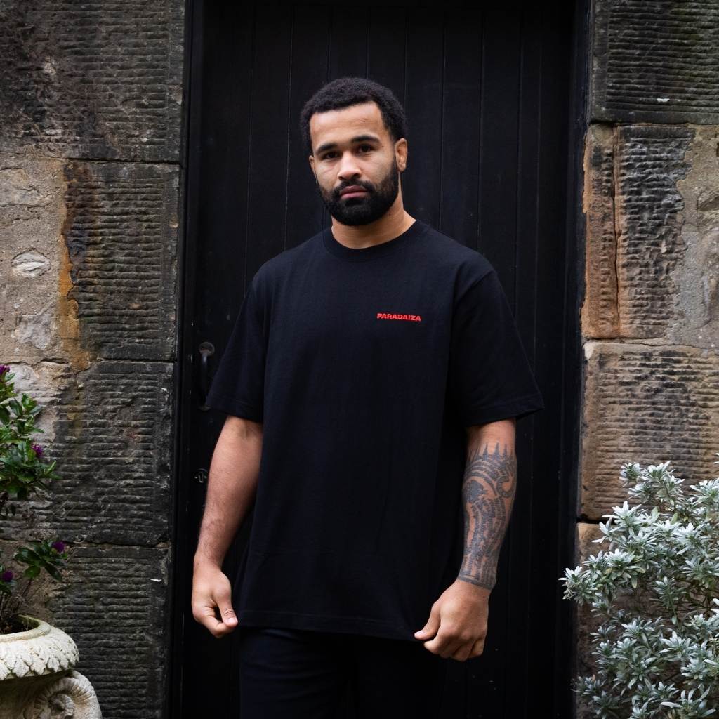 man wearing Paradaiza Black t-shirt with a graphic design on the back against wall in stockbridge 