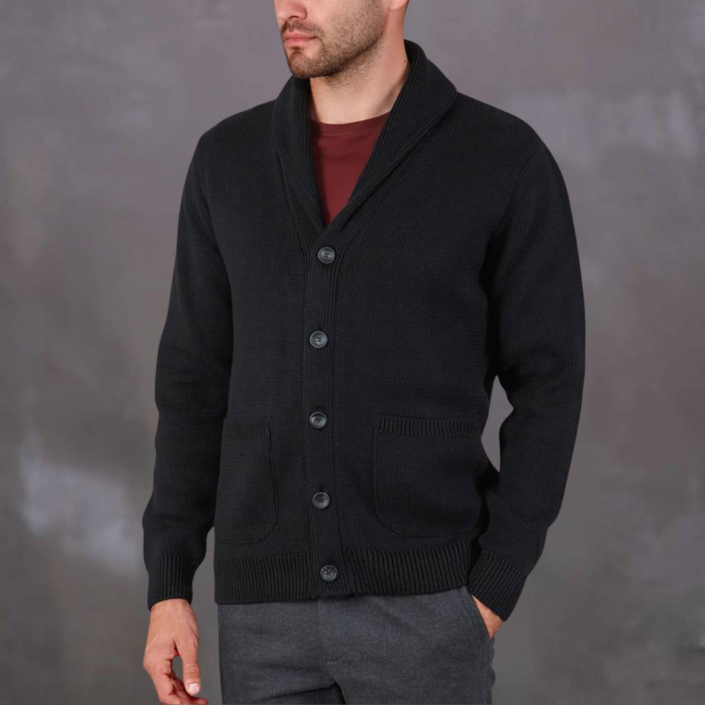 Man wearing a navy paradaiza cardigan over a red shirt against a gray background