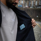 Man wearing a  paradaiza wool worker black jacket standing in front of a stone wall in circus lane stockbridge 
