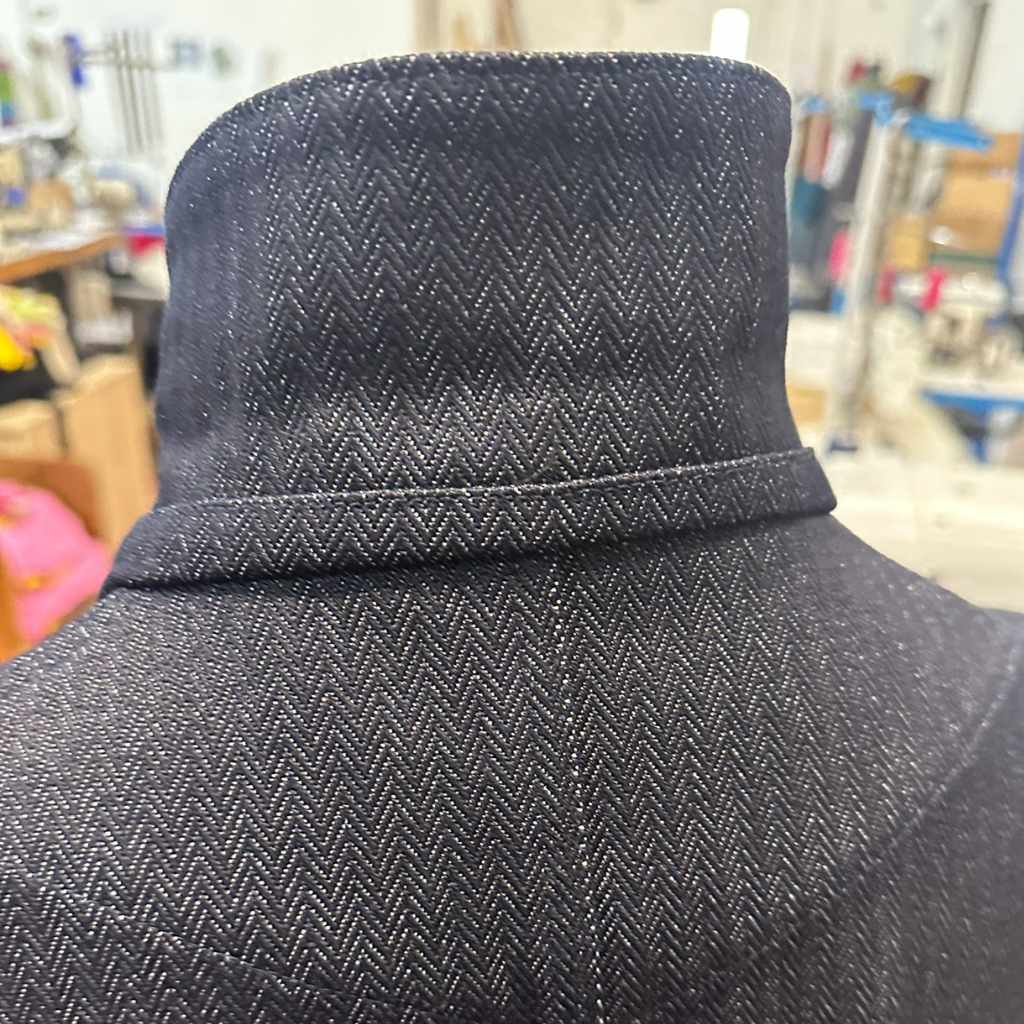 Close-up of a paradaiza herringbone orta denim jacket  with a blurred indoor background