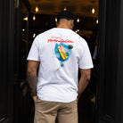 Person wearing paradaiza  white t-shirt with a colorful graphic on the back, standing in a doorway of paradaiza stockbridge 