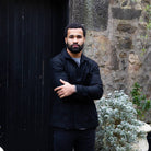 Man wearing a  paradaiza wool worker black jacket standing in front of a stone wall in circus lane stockbridge 