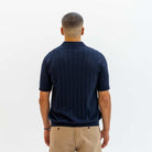 Man wearing a paradaiza navy blue polo shirt in a clothing store.