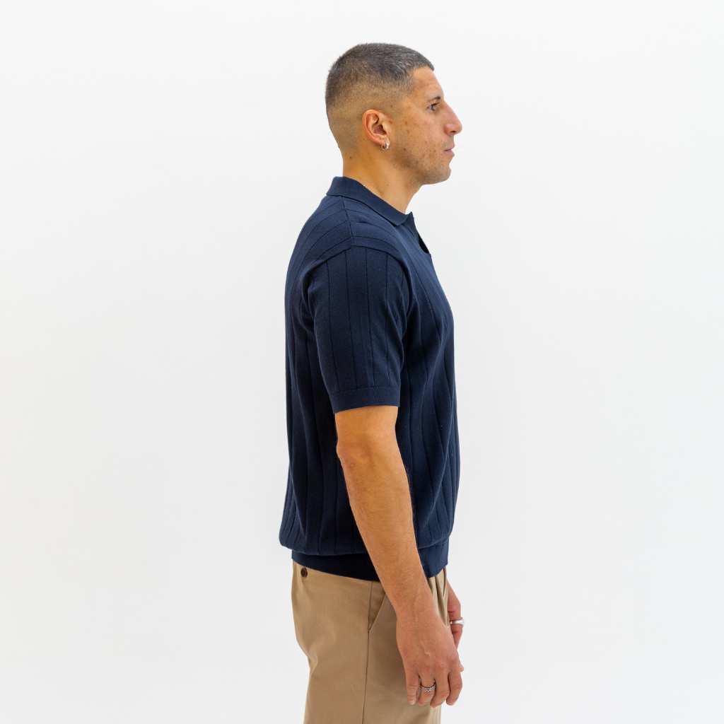 Man wearing a paradaiza navy blue polo shirt in a clothing store.