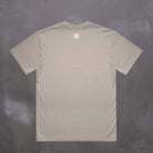 Beige paradaiza  t-shirt with a logo on the back against a dark background