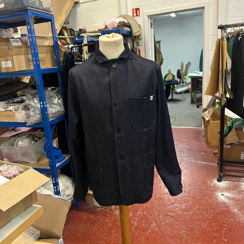 paradaiza rail worker  jacket on a mannequin in a warehouse setting with shelves and boxes in the background.