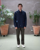 Model wearing a  paradaiza dark blue worker jacket with patterned accents and sashiko stitching  wearing khaki chinos  in a studio.