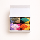 Set of colorful argyle patterned socks in a white box on a light background
