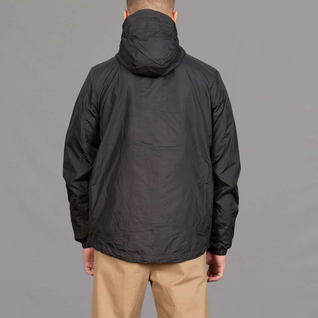 Model wears a Black Commuter Jacket, Lightweight and crafted with 100% recycled polyester. It is designed with a longer curved hem at the back, which provides extra coverage. The hood visor and welt pockets are sealed for additional weatherproofing, and the hood is also double-layered with an adjustable plastic stopper and interior elastic cord.