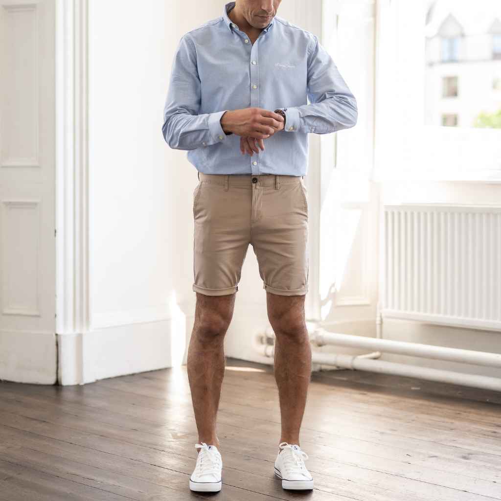 model wears paradaiza blue button down oxford shirt and chino shorts