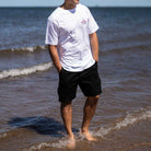 model wears paradaiza black cargo shorts and tee in the sea