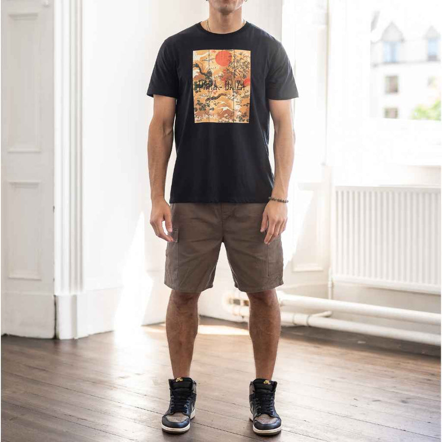 A person standing wearing a Paradaiza black T-shirt and brown cargo shorts with a patterned drawstring.