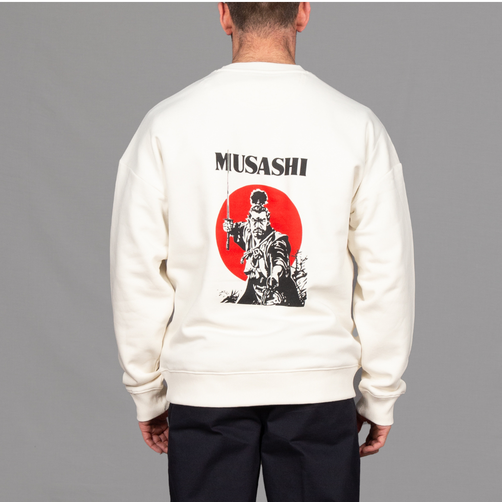 model wears a white sweatshirt with musashi graphic with navy chinos