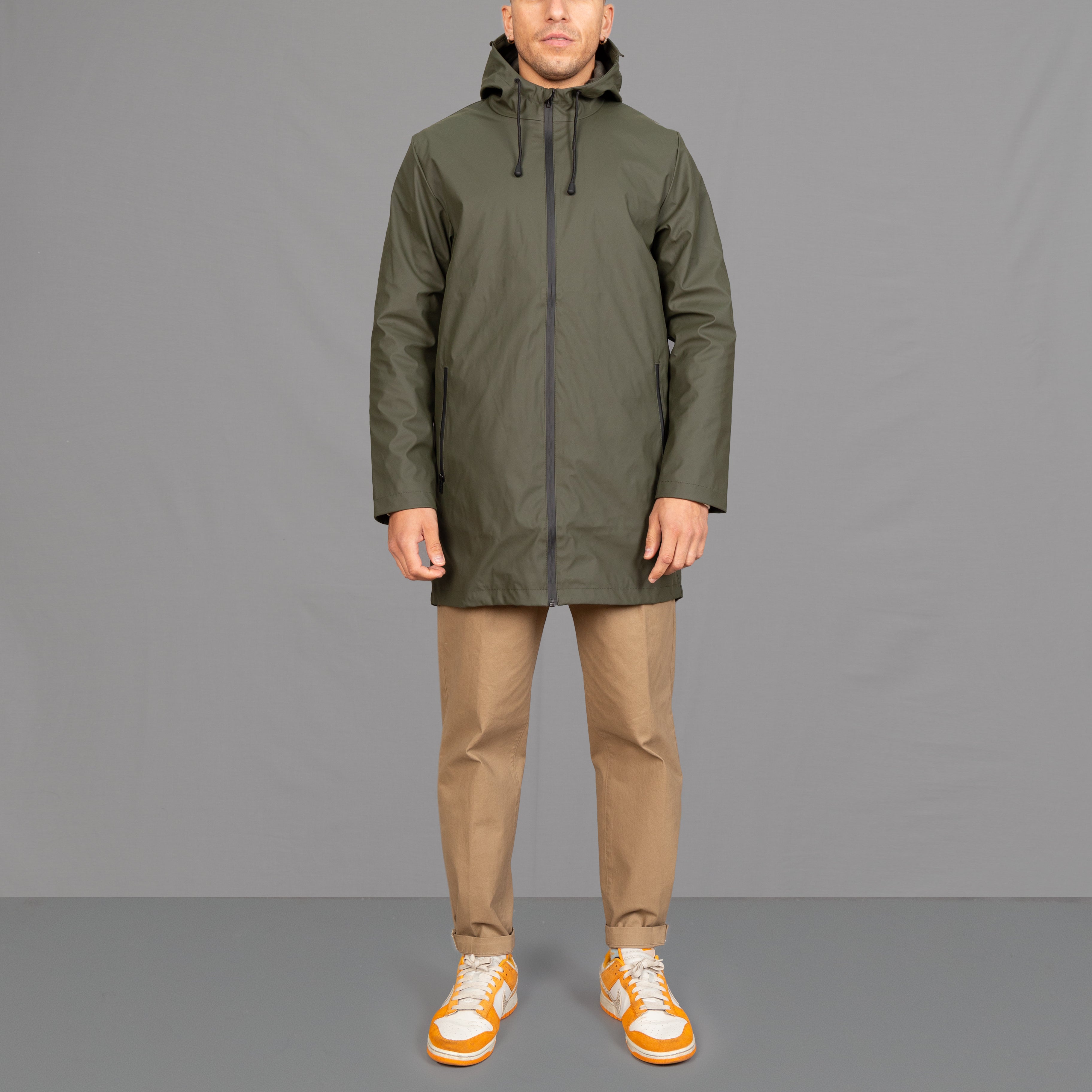 model wears a khaki waterproof parka and chinos