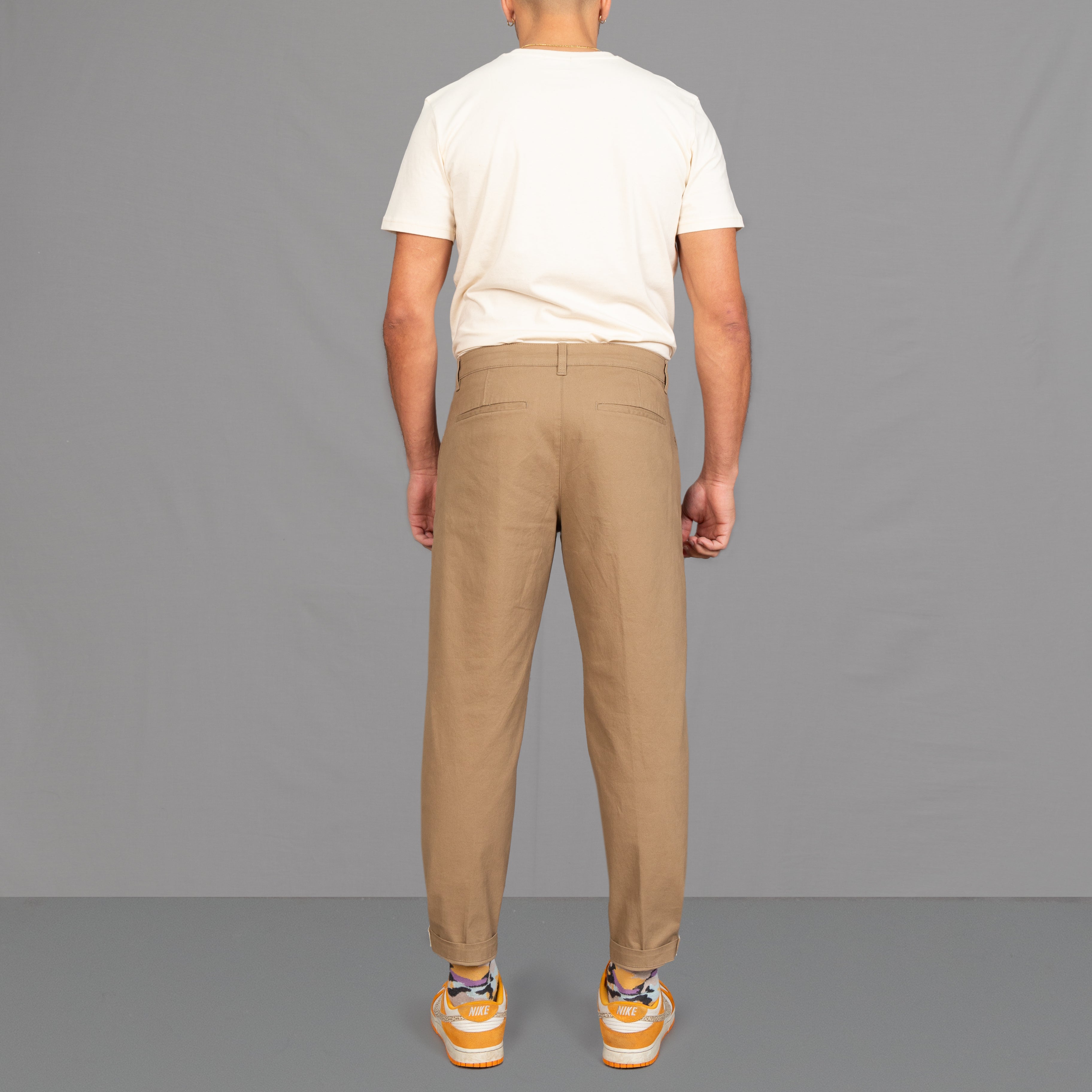 model wears para-daiza tan pinch chinos with nike sneakers