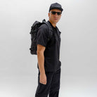 Person wearing a black PARADAIZA backpack with a visible brand logo on a plain background