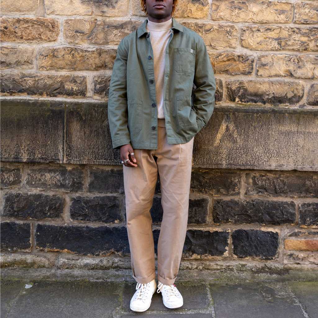 Man wearing a paradaiza worker jacket and sunglasses against a brick wall