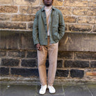 Man wearing a paradaiza worker jacket and sunglasses against a brick wall