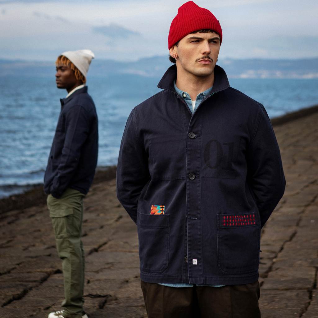 Model wearing a  paradaiza dark blue worker jacket with patterned accents and sashiko stitching  