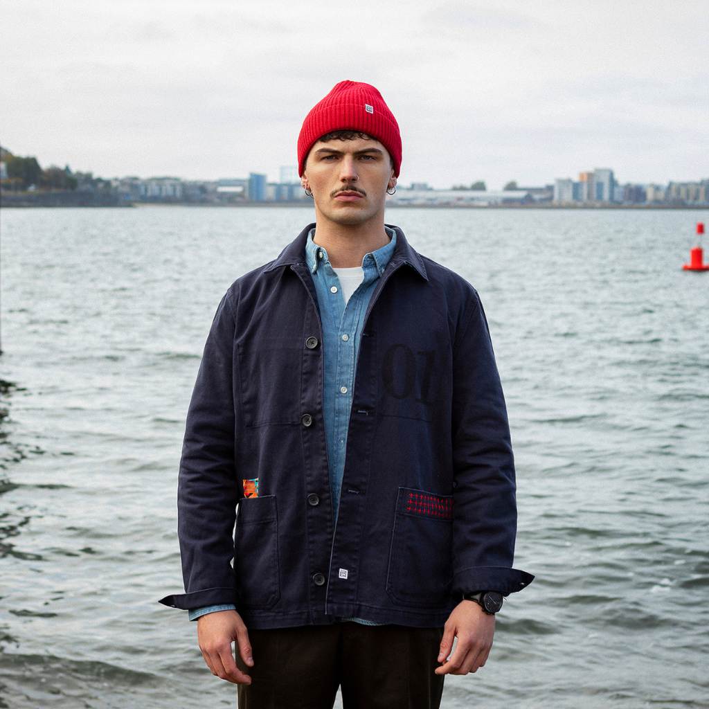 Model wearing a  paradaiza dark blue worker jacket with patterned accents and sashiko stitching  