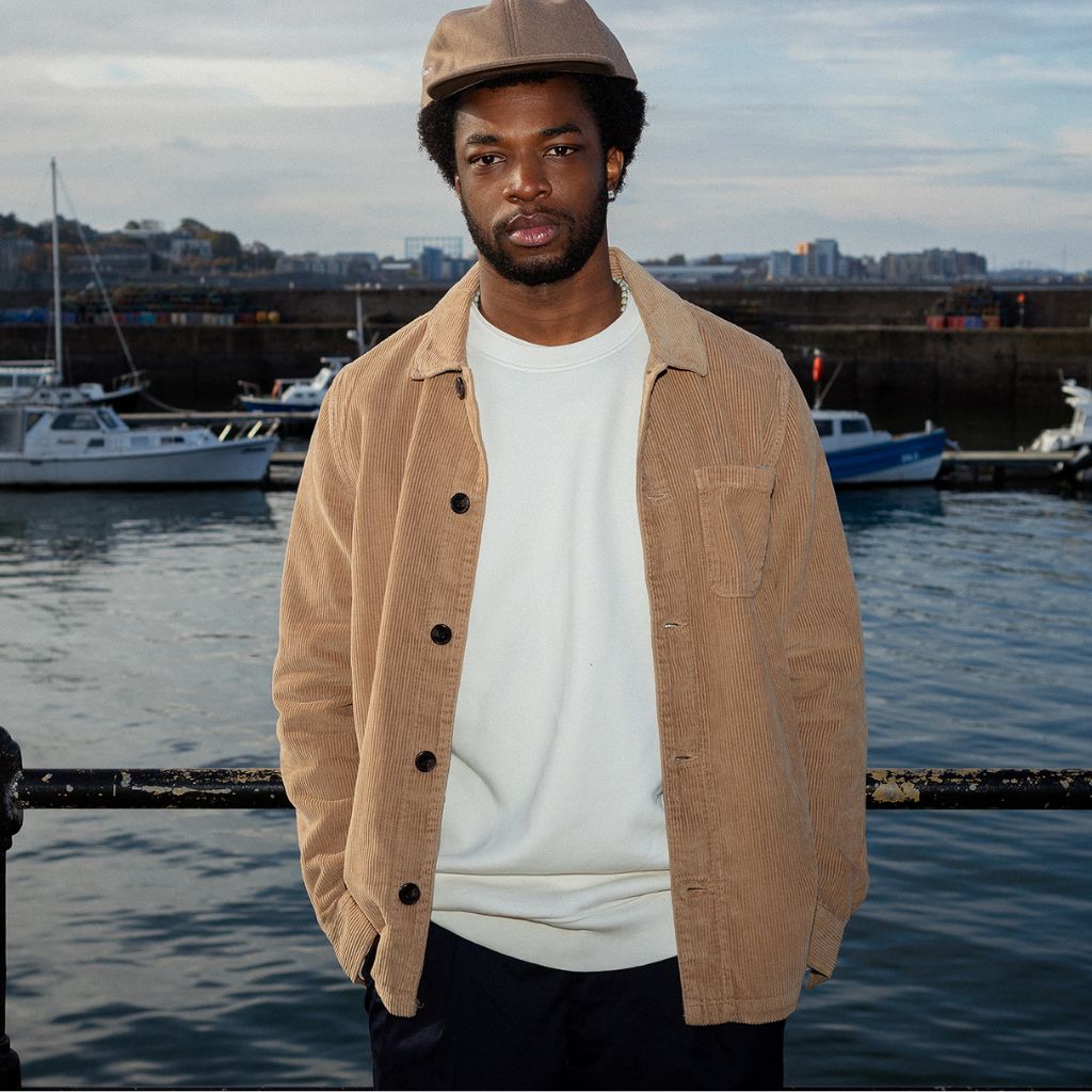 A person wearing a Paradaiza tan corduroy overshirt with a collar, buttons, and a patch chest pocket.
