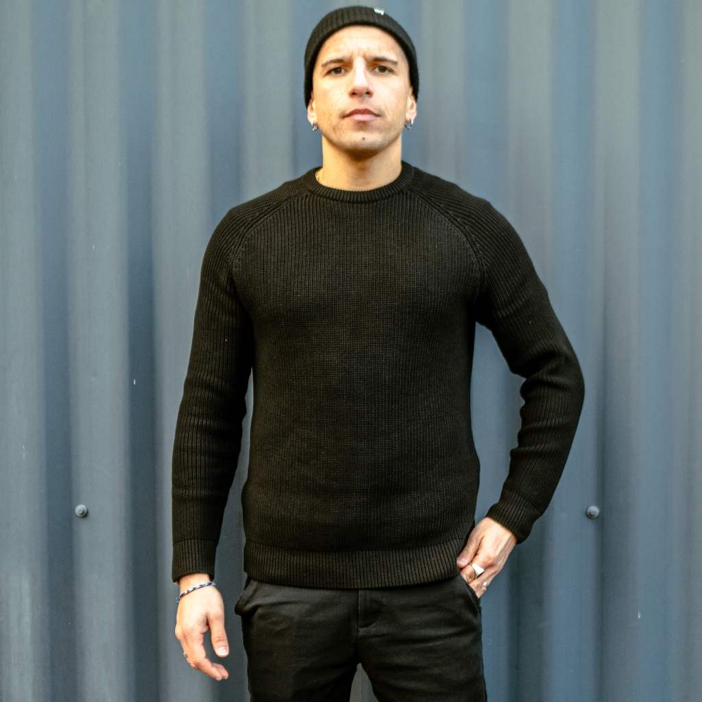 Man wearing a paradaiza black knit against a gray background