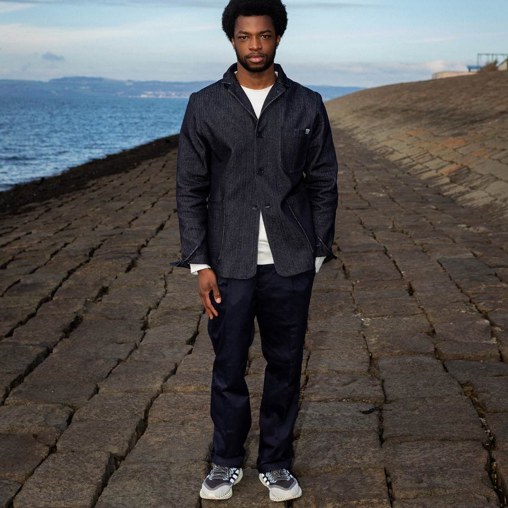 Man wearing a paradaiza dark denim jacket against a gray background