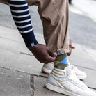 Person wearing white new balance sneakers, paradaiza pinch chinos beige pants, and patterned socks on a sidewalk.