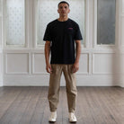 Man wearing a Paradaiza  black t-shirt with a small pink logo against a neutral background