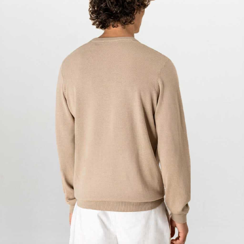 Person wearing a paradaiza beige sweater and white pants on a light gray background