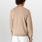 Person wearing a paradaiza beige sweater and white pants on a light gray background