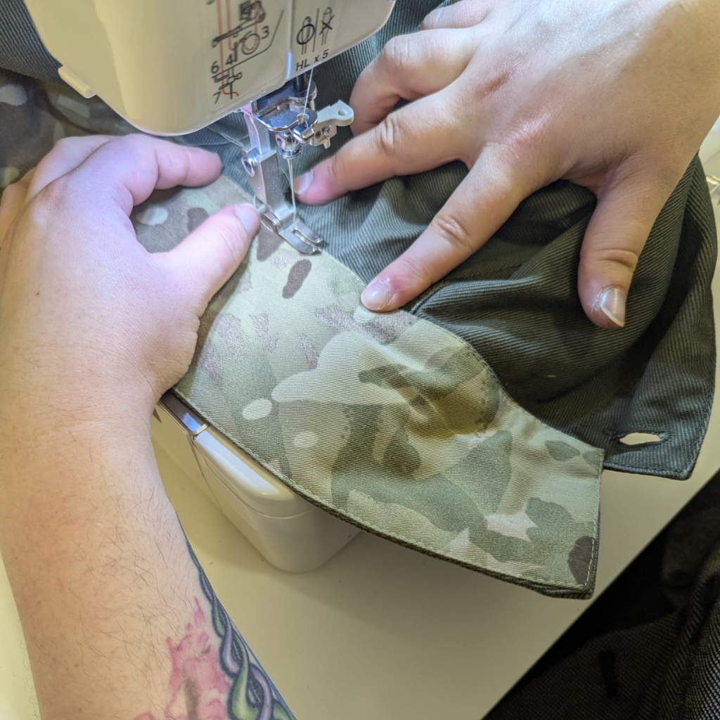 Person sewing a camouflage PARA-DAIZA fabric on a sewing machine.
