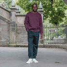 Person wearing a paradaiza maroon sweatshirt against a stone wall background
